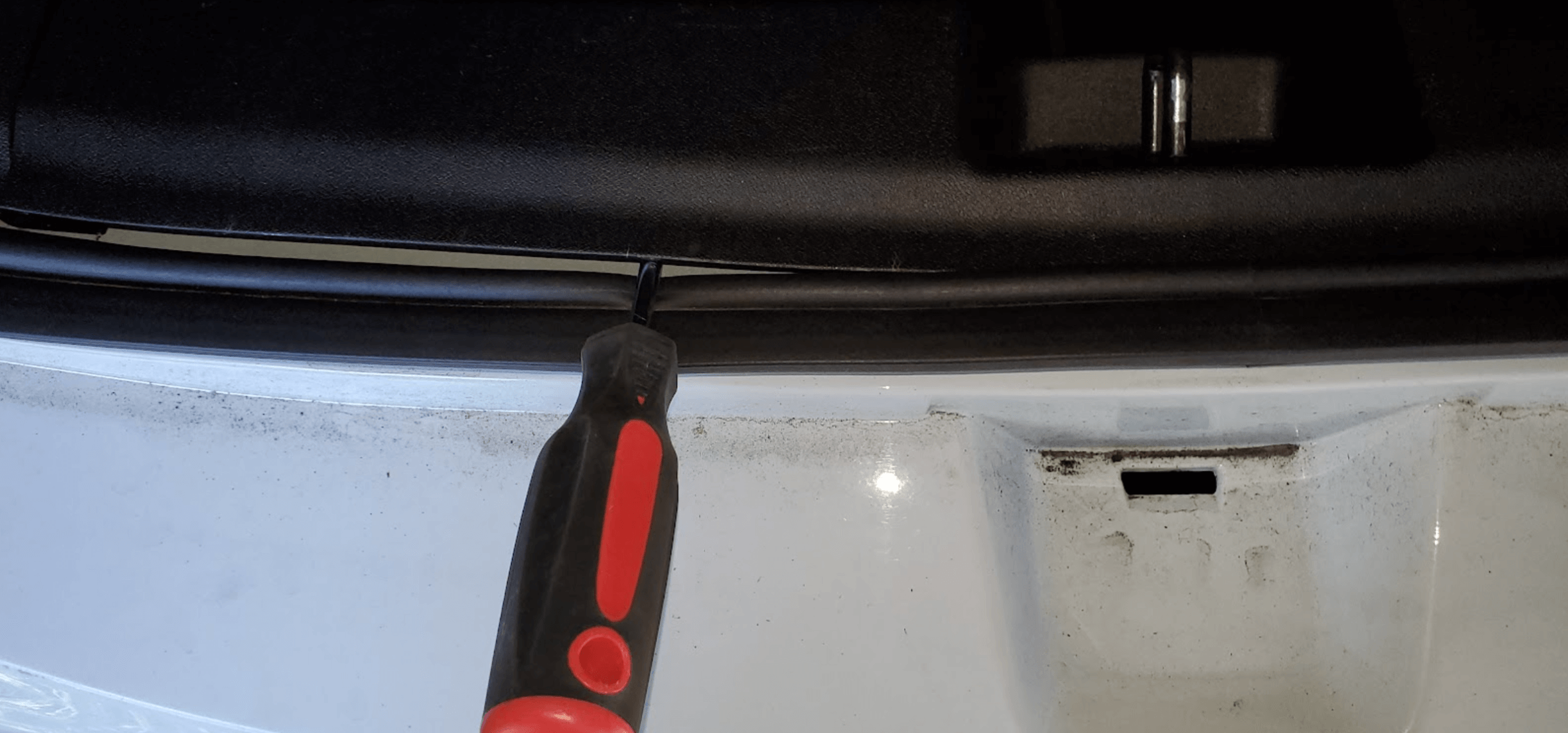 The back edge of plastic piece near trunk latch